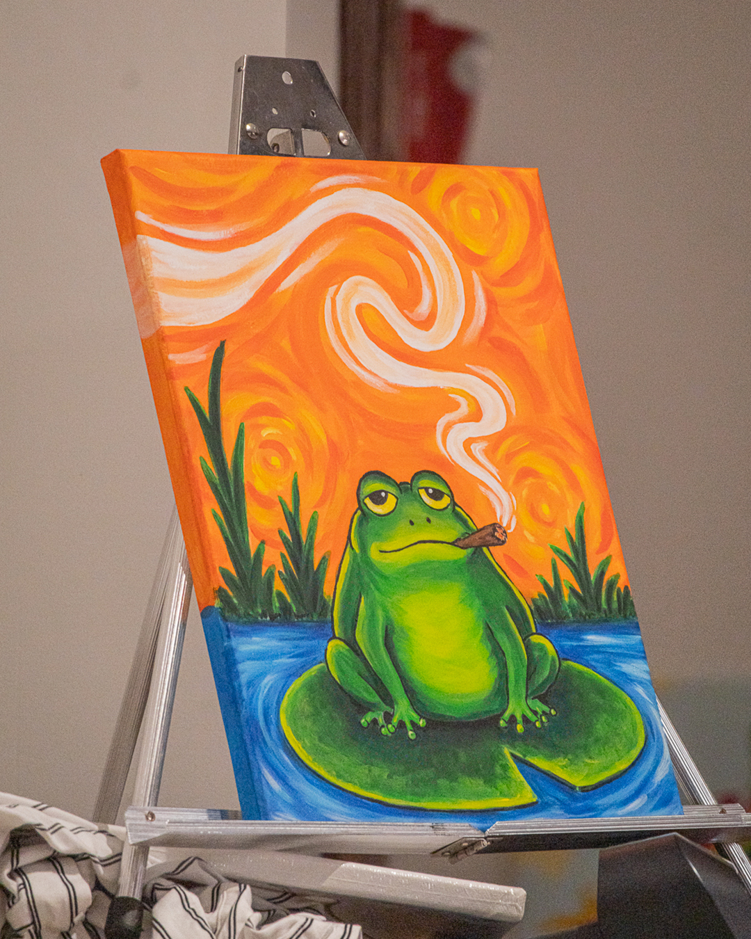Finished frog painting on an easel at the Puff N Paint class at 6 Point Flower Shop
